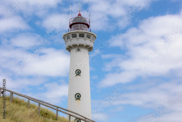 Obraz The J.C.J. van Speijk Lighthouse tower with european marram grass (beach grass) under blue sky in summer, Dutch north sea coastline, Egmond aan Zee, Municipality of Bergen, Noord Holland, Netherlands.