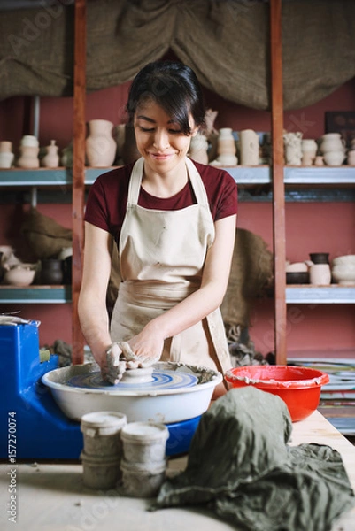 Obraz Beautiful woman working at pottery wheel in studio