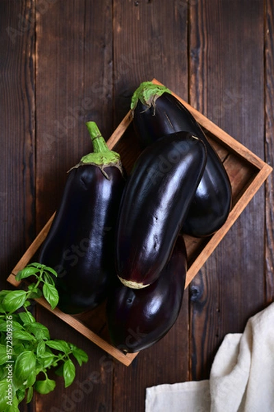 Fototapeta organic eggplant harvest in crate on log background, flat lay