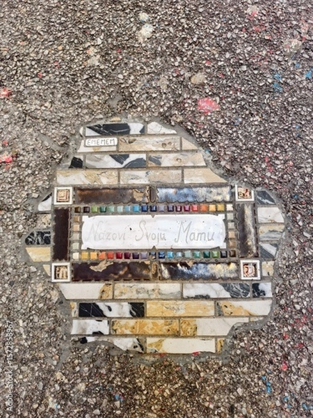 Fototapeta Artistic Tile Repairs in Urban Pavement Featuring message "Call your mother"