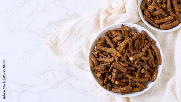 Fototapeta flat lay pile of dry dandelion root herb for loose tea in bowl on white table background with copy space