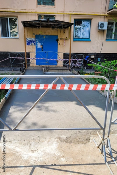 Obraz Asphalt repair with warning tape around the entrance residential building.