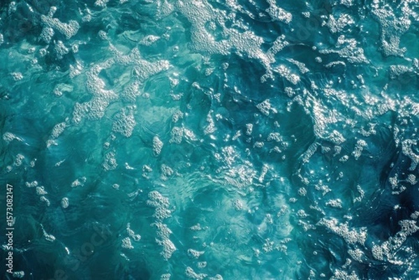 Obraz Top view of ocean surface with white sea foam and sun reflections. Clear turquoise water. Natural texture. Clean and refreshing summer atmosphere. Perfect for backgrounds and nature concepts. Banner