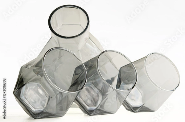 Obraz Modern decanter and three angled whiskey glasses in tinted glass create an elegant composition ideal for stylish kitchen or living room decor. Crisp white background accents. Photo