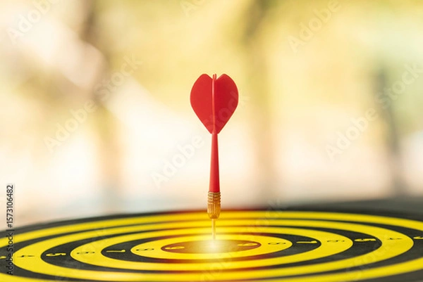 Fototapeta Red dart hitting the bullseye of a target. A concept of business success, achieving a goal, and strategic focus. Symbol of precision, achievement, and marketing objective.