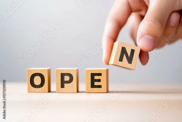 Fototapeta A hand holding a letter block to change the word OPEN emphasizes accessibility and welcoming environments in business and hospitality settings.