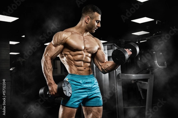 Fototapeta Handsome man with big muscles, posing at the camera in the gym