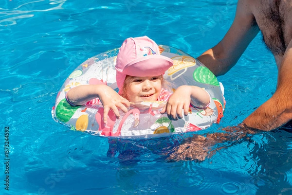 Fototapeta Family Dad and Daughter Swim in Pool on Sunny Day in Summer with Inflatable Ring