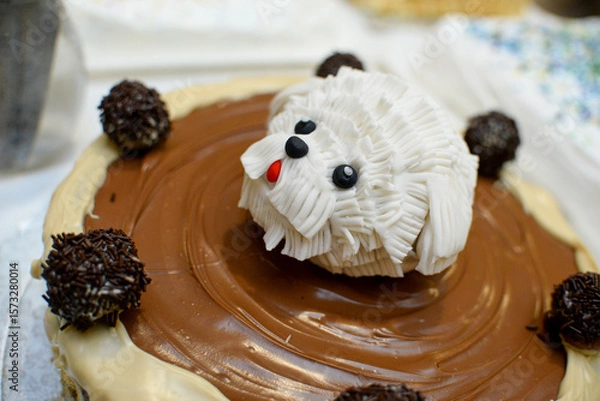 Fototapeta A round chocolate birthday cake decorated with chocolate in various shades and a fondant dog head in the middle