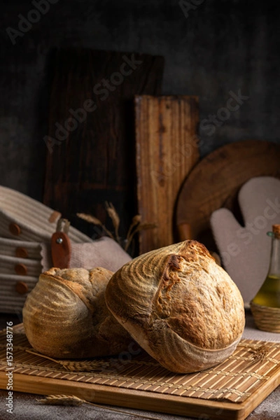 Fototapeta Healthy, organic, whole and sliced ​​homemade sourdough bread with ham and cheese on a wooden table and kitchen utensils with an airy crumb and crispy crust. 