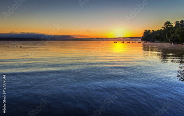 Obraz Foggy Summer Lake Sunrise Panorama. Sunrise over Lake Superior on a foggy summer morning with a small wooden dock at the horizon.
