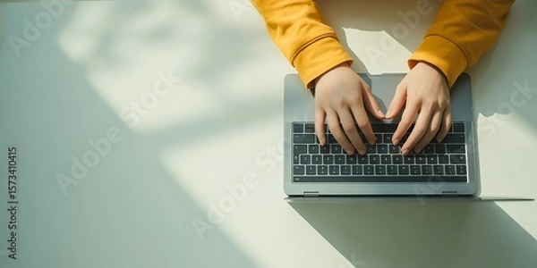 Fototapeta Hands typing on a laptop keyboard under soft sunlight, showcasing remote work, digital nomad lifestyle, and online communication.