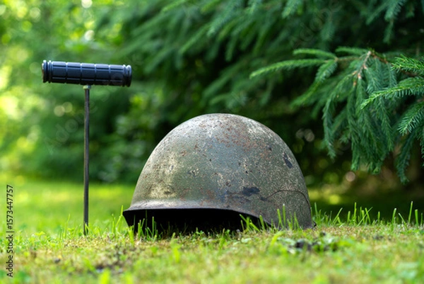 Fototapeta A probe for searching in the ground.An old military soldier's helmet is lying on the ground. Search on the battlefield.
