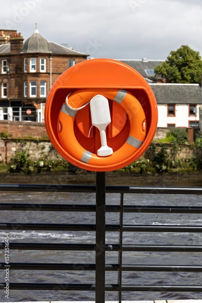 Obraz Riverside Safety: Orange Lifebuoy in Housing on Railings