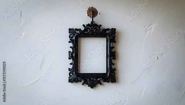 Fototapeta Black silhouette of an ornate baroque picture frame hanging crookedly from a rustic nail on a pure white background, emphasizing themes of memory, absence, and decorative historical emptiness