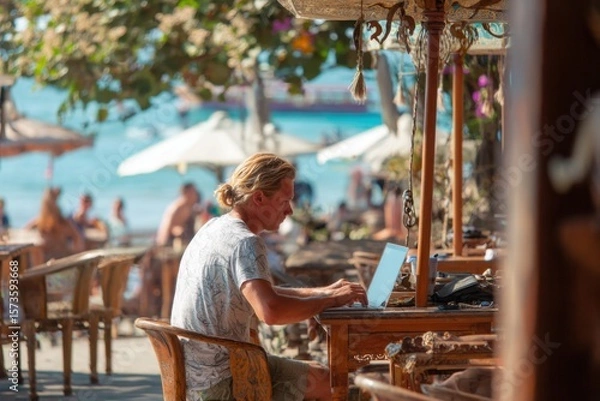 Obraz Person Working on Laptop at Beachside Cafe with Scenic View