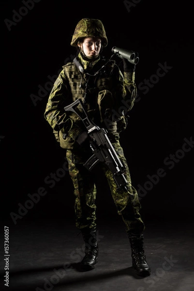 Fototapeta Portrait of armed woman with camouflage. Young female soldier observe with binoculars. Child soldier with gun in war, hause ruins background.  Military, army people concept