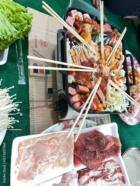Obraz Hot Pot Array: A vibrant array of ingredients displayed for hot pot cooking, featuring raw meat, fresh vegetables, and skewered items ready to be immersed in flavorful broth, inviting shared meals