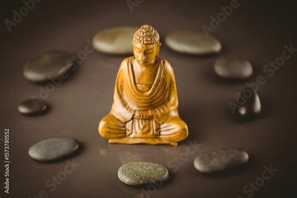 Fototapeta Buddha sculpture surrounded by pebbles