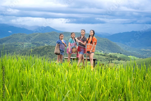 Fototapeta Group of pretty teenage travellers wearing custom-made Karen dresses in a natural green terraced rice fields at Pa Bong Piang rice fields, Mae Chaem, Doi Inthanon, Chiang Mai, Thailand.