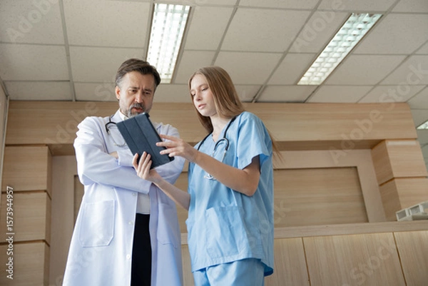 Obraz Caucasian woman doctor use tablet computer with team working at hospital	
