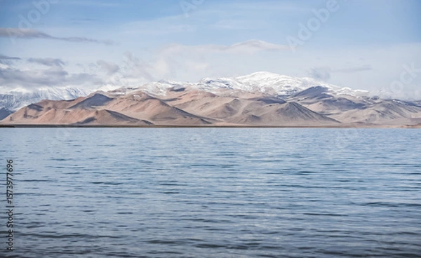 Fototapeta Panorama landscape of Lake Karakul in the Pamir mountains in the Tien Shan against the background of high snowy rocky peaks with clouds, morning panorama of the lake for the background