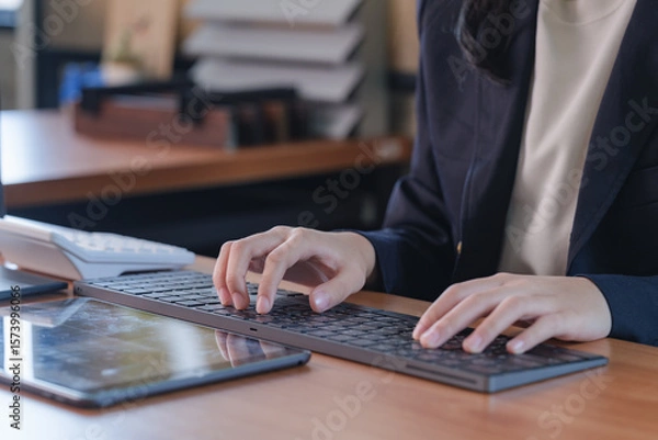 Fototapeta Close-up hand of an Asian businesswoman typing on a keyboard.