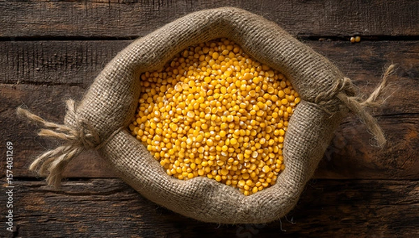 Fototapeta Rustic burlap sack filled with yellow soybeans on vintage wooden table under warm light in agricultural still life composition