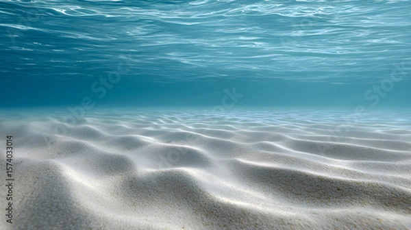 Obraz Underwater scene showcasing soft sandy ocean floor with gentle ripples, illuminated by sunlight filtering through clear blue water, creating a serene aquatic atmosphere