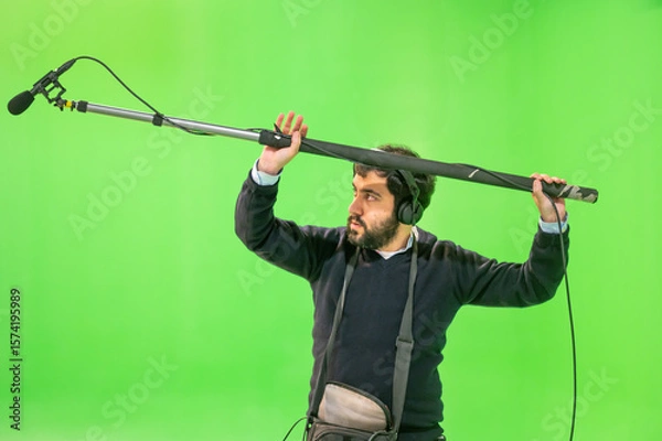 Fototapeta Boom microphone operator testing sound at TV studio on green key chroma background. High quality photo