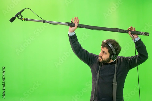 Fototapeta Boom microphone operator testing sound at TV studio on green key chroma background. High quality photo
