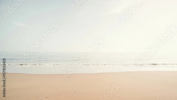 Fototapeta Sandy beach with gentle waves meeting the shore under a hazy sky serene coastal landscape with soft colors and a tranquil atmosphere