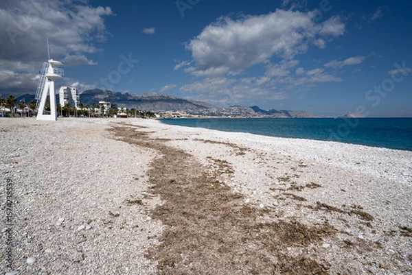 Fototapeta Looking North towards Calpe on the the beautiful White pebble beach of Platja Cap Blanc near El Albir in Spain