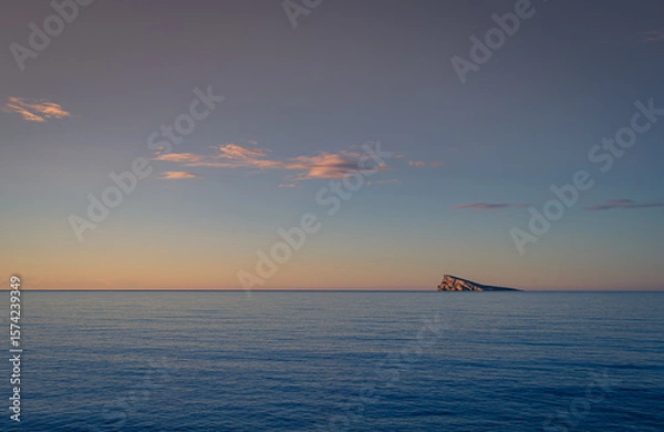 Fototapeta Just after sunrise and the cliffs on Benidorm Island reflect the early morning sunlight