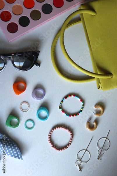 Obraz Green bag, various colorful jewelry, sunglasses, hair accessories and colorful make up on white background. Flat lay.