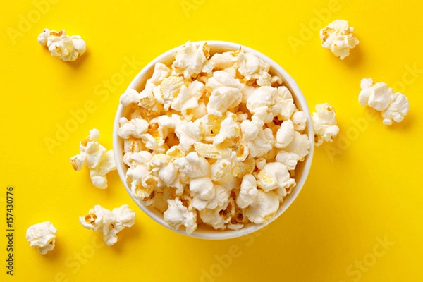Fototapeta Popcorn viewed from above on yellow background. Flat lay of pop corn bowl. Top view