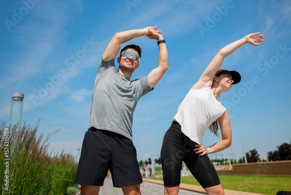 Fototapeta Stretching in the park on a sunny day with friends enjoying outdoor fitness