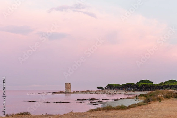 Fototapeta Coastal watchtower by calm sea under soft pastel sky during twilight at Mediterranean beach