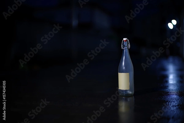 Fototapeta Empty Glass Bottle with Label on Wet Street at Night