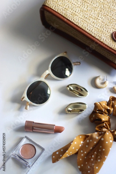 Obraz Wicker purse, sunglasses, scrunchie, lipstick and various gold and neutral jewelry on white background. Selective focus.