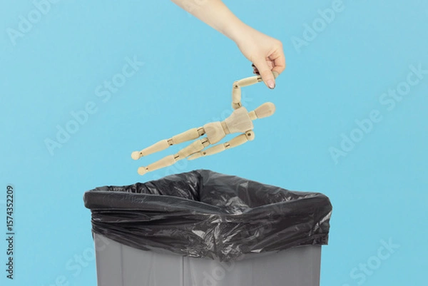 Fototapeta Throw wooden man, in the trash, outstretched hand with wooden mannequin in front of trash can