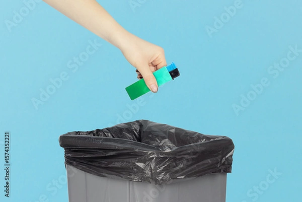Fototapeta throw the lighter in the trash, outstretched hand with a lighter in front of the trash can, the concept of the dangers of smoking cigarettes, quitting smoking