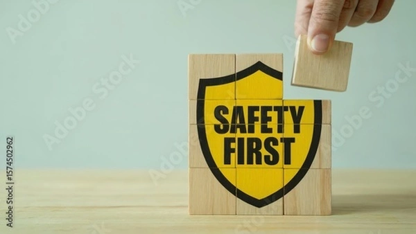 Obraz Blocks display the phrase Safety First with a hand about to put a block on top