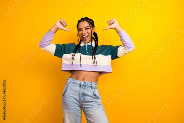 Fototapeta Happy young woman showing confident gesture with both hands against yellow background