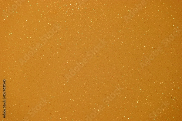 Fototapeta Sparkling golden surface with shimmering particles captured under bright light in a creative setting