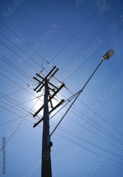 Fototapeta Power pole and lines with sun back lit.