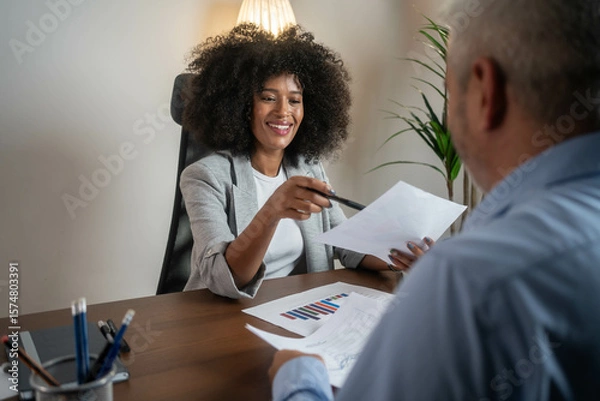 Fototapeta Corporate banker and client analyzing financial contract or business plan in professional office setting.