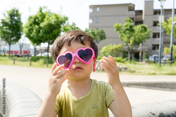 Obraz ハートのサングラスをかけた男の子がスイーツを楽しむ夏の屋外ポートレート｜家族レジャー・お祭りイメージに最適な子ども写真