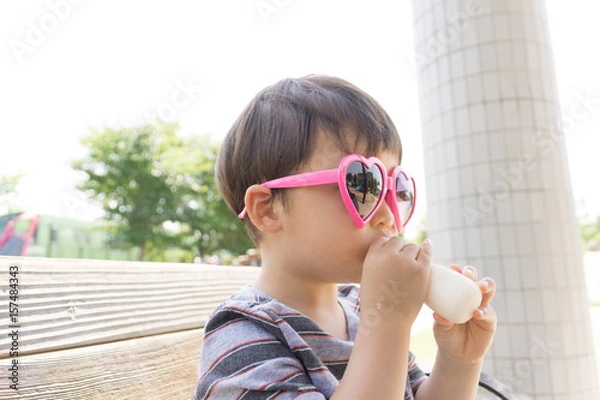 Obraz ハートのサングラスをかけた男の子がスイーツを楽しむ夏の屋外ポートレート｜家族レジャー・お祭りイメージに最適な子ども写真