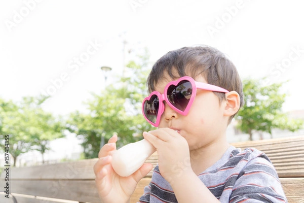Obraz ハートのサングラスをかけた男の子がスイーツを楽しむ夏の屋外ポートレート｜家族レジャー・お祭りイメージに最適な子ども写真